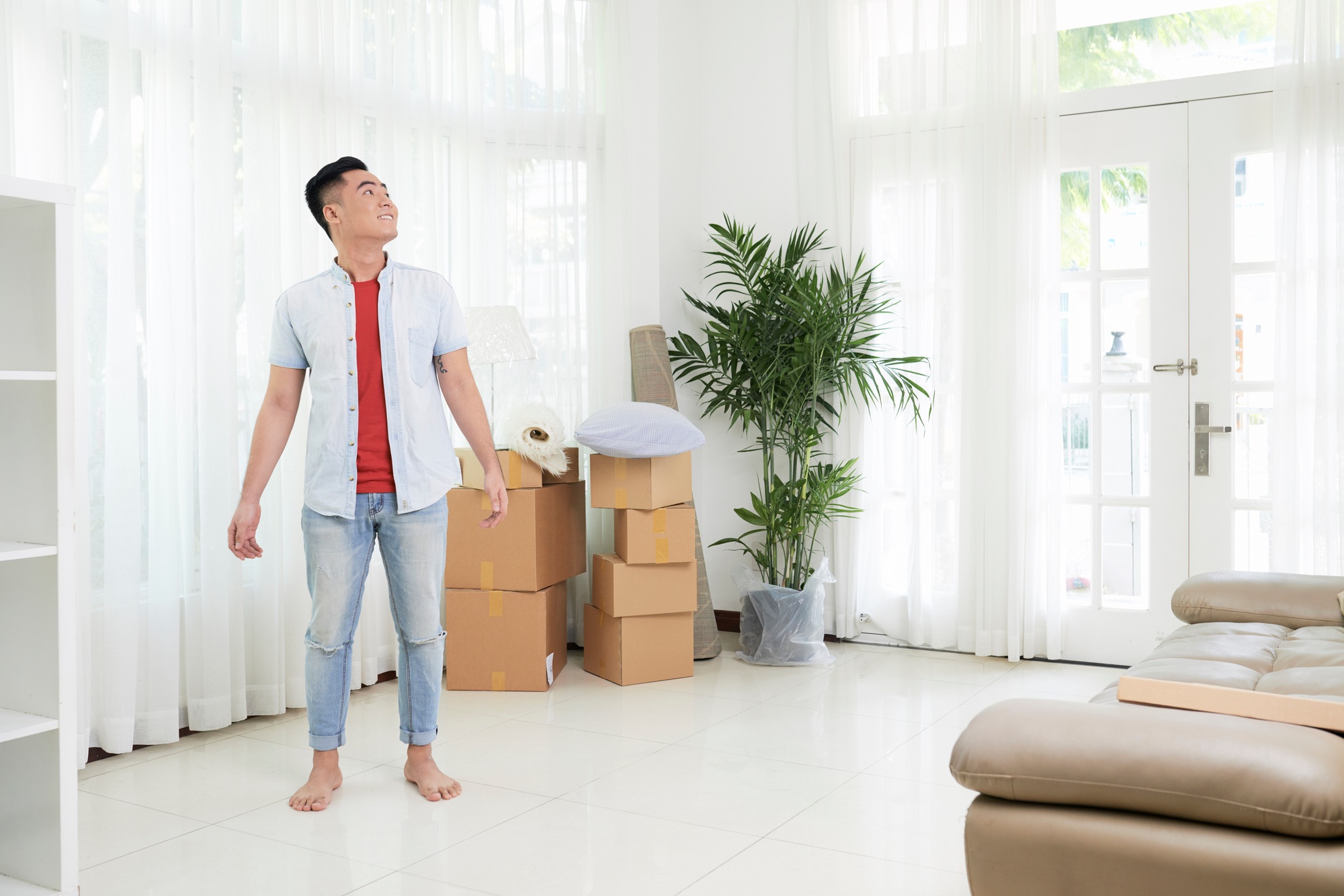 Content Asian man standing in new apartment